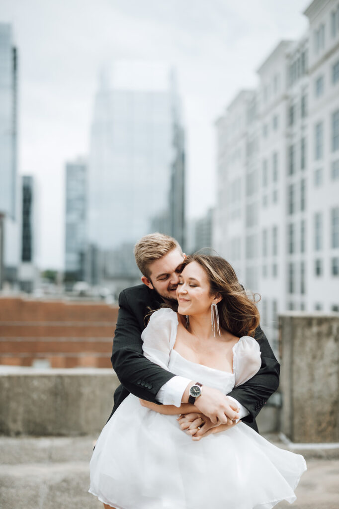 bride and groom hugging and nuzzling on a rooftop in Nashville, TN