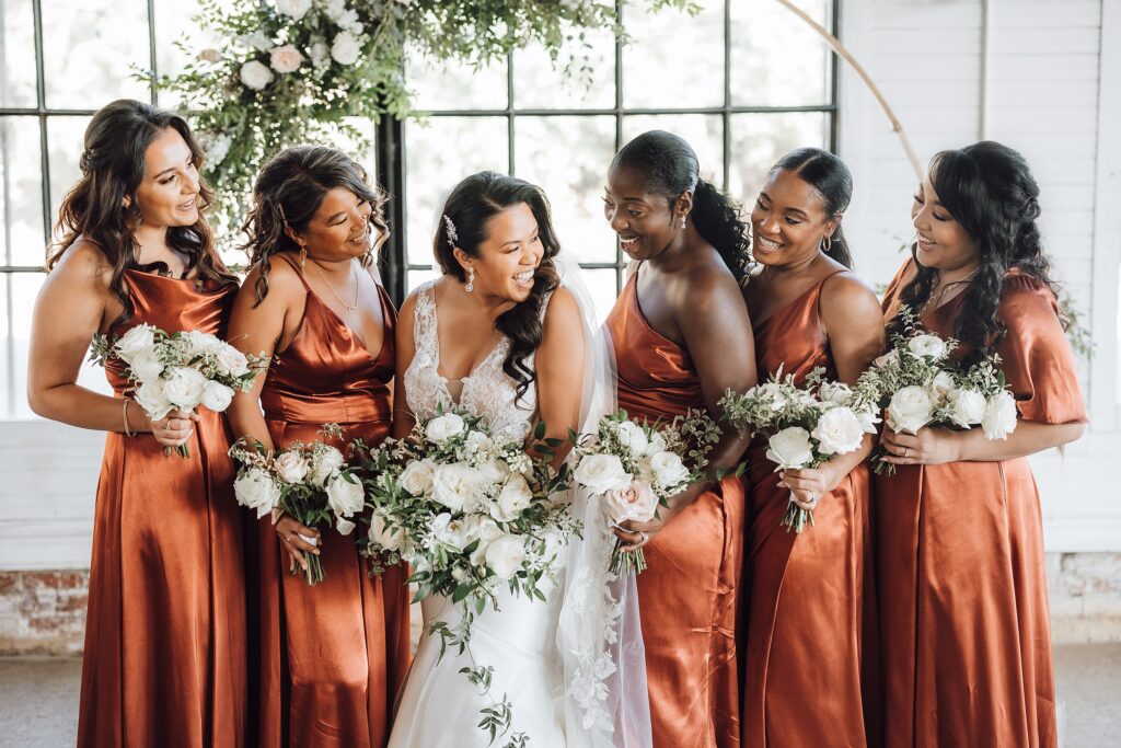 bridal party in rust colored gowns laughing with the bride at their Ozari Nashville wedding