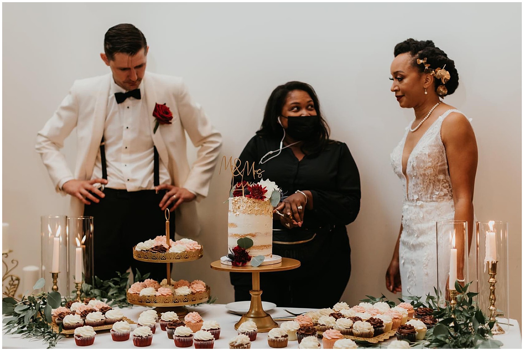 Wedding planner in black clothes teaches newlyweds how to cut their cake PLS Coordinate