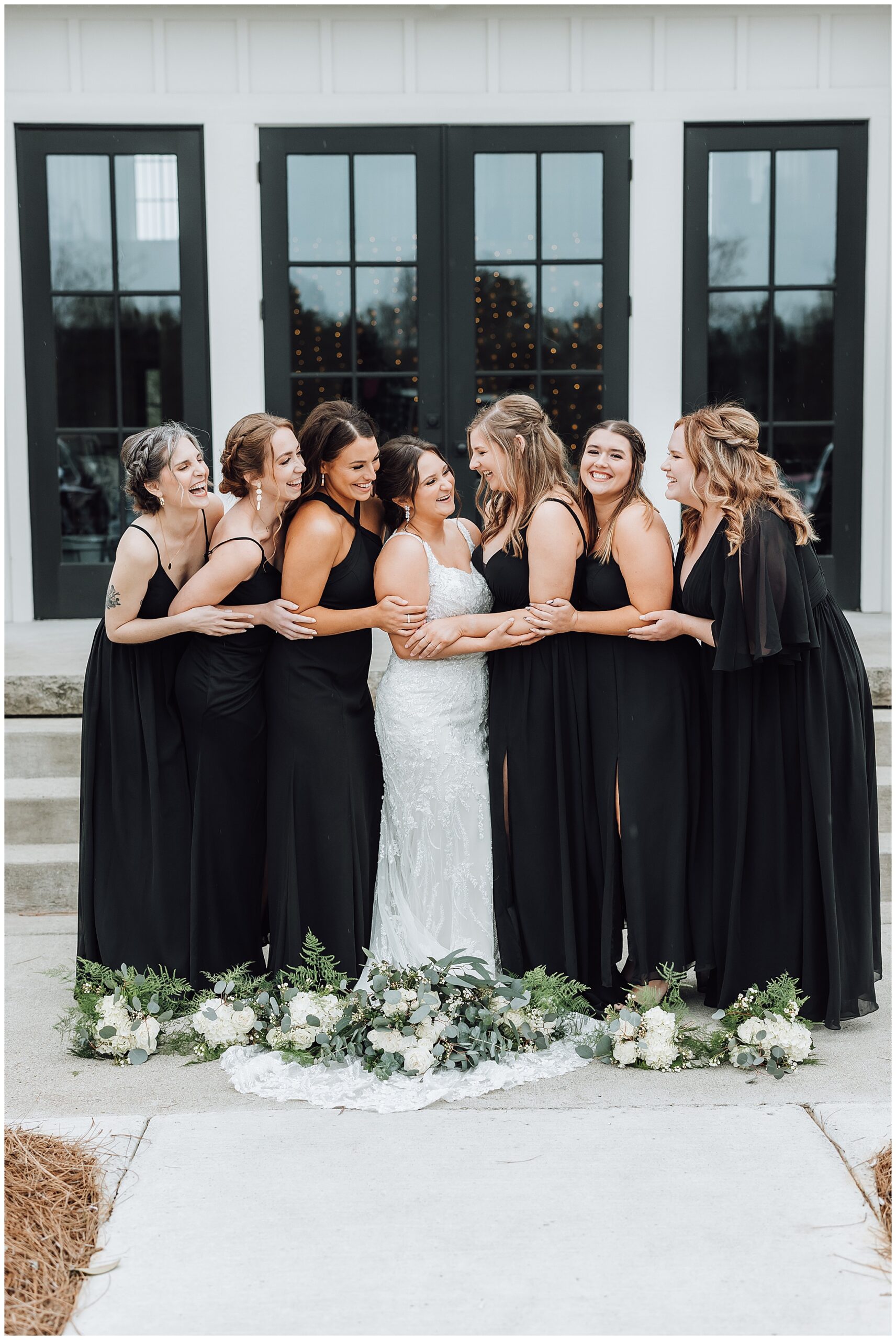Bridal party all hug on the bride with their bouquets at their feet