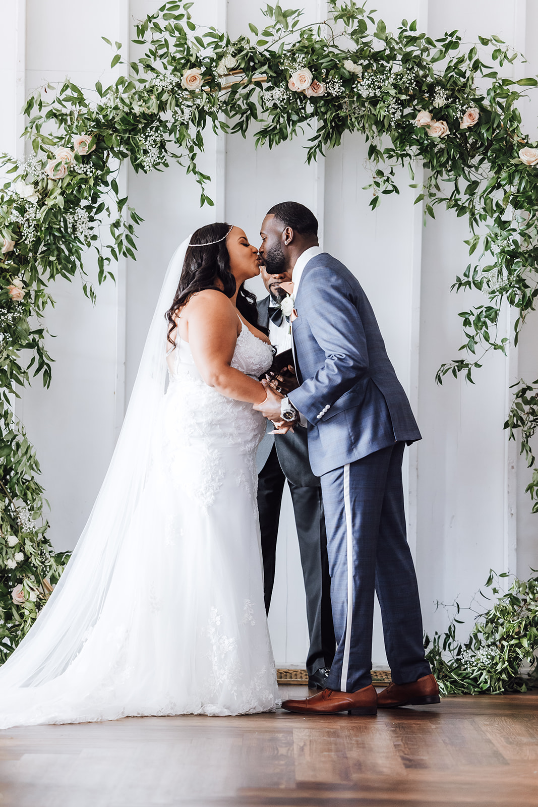 Newlyweds kiss under a flower arch during their ceremony 14Tenn Wedding