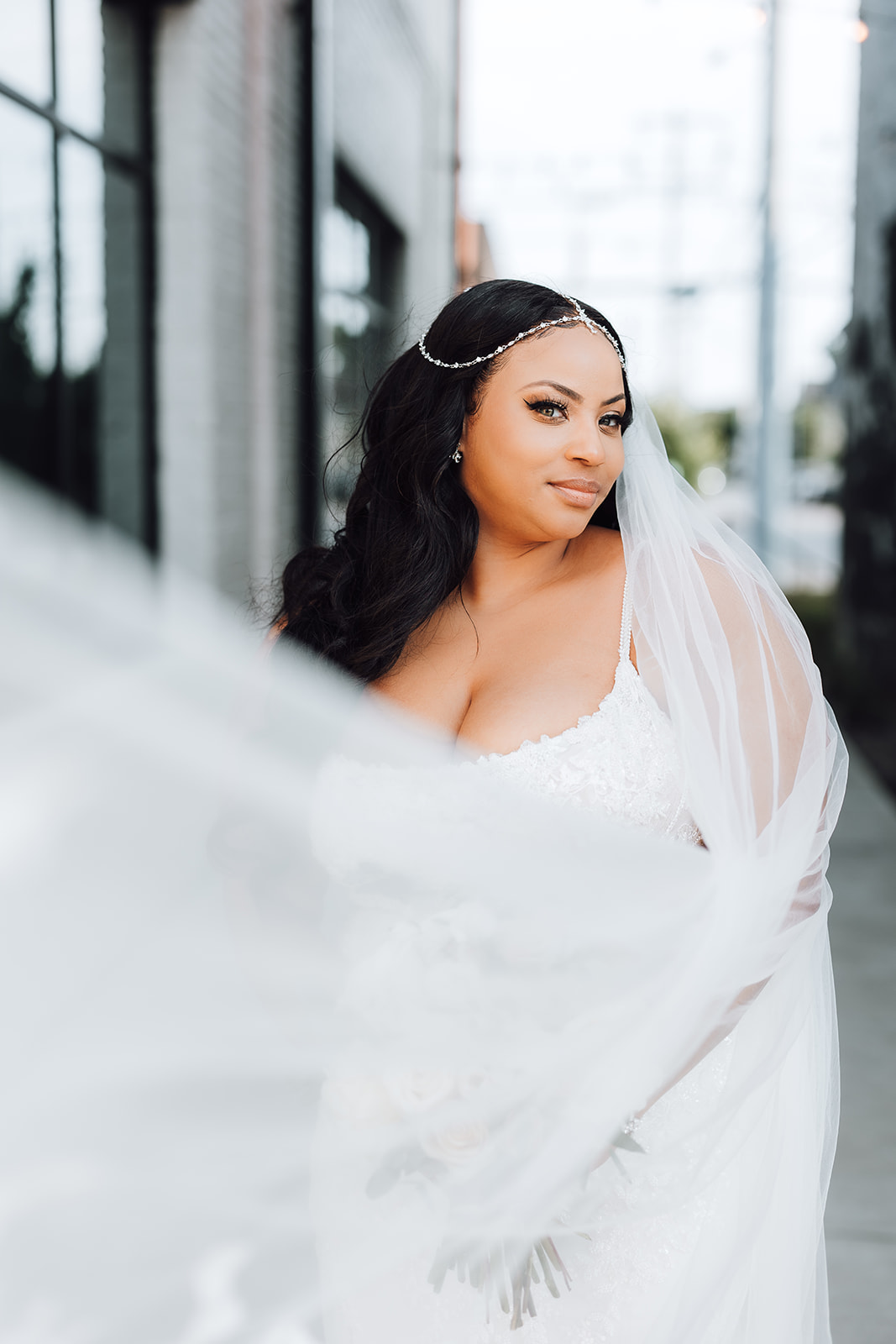 A bride stands in an alley while her veil blows in the wind around her 14Tenn Wedding