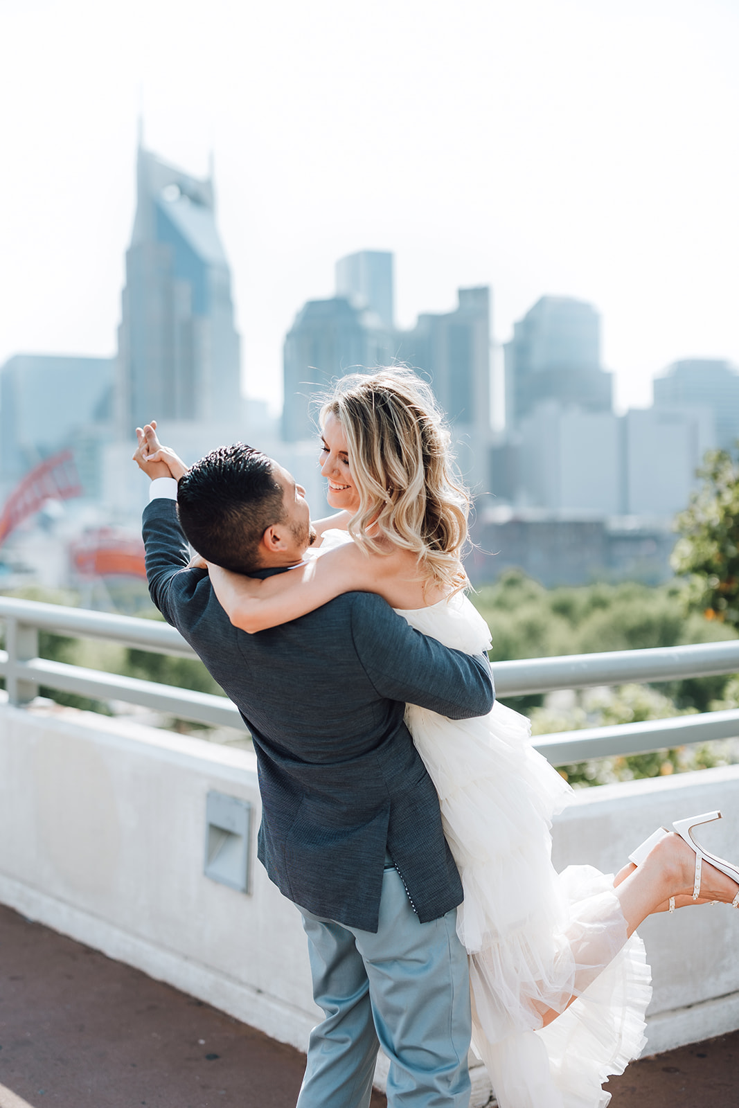 A groom lifts his bride as they dance on a rooftop at The Bridge Building Nashville