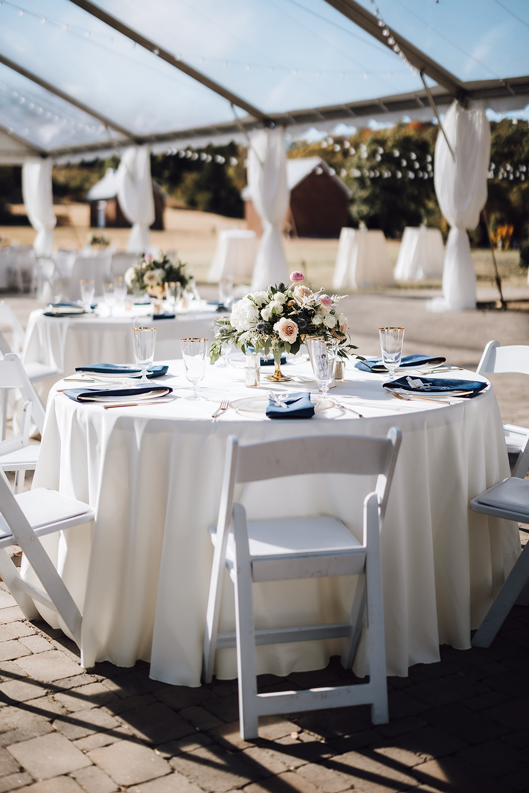A wedding reception table with white linens and blue napkins and gold-rimmed glasses Ravenswood Mansion