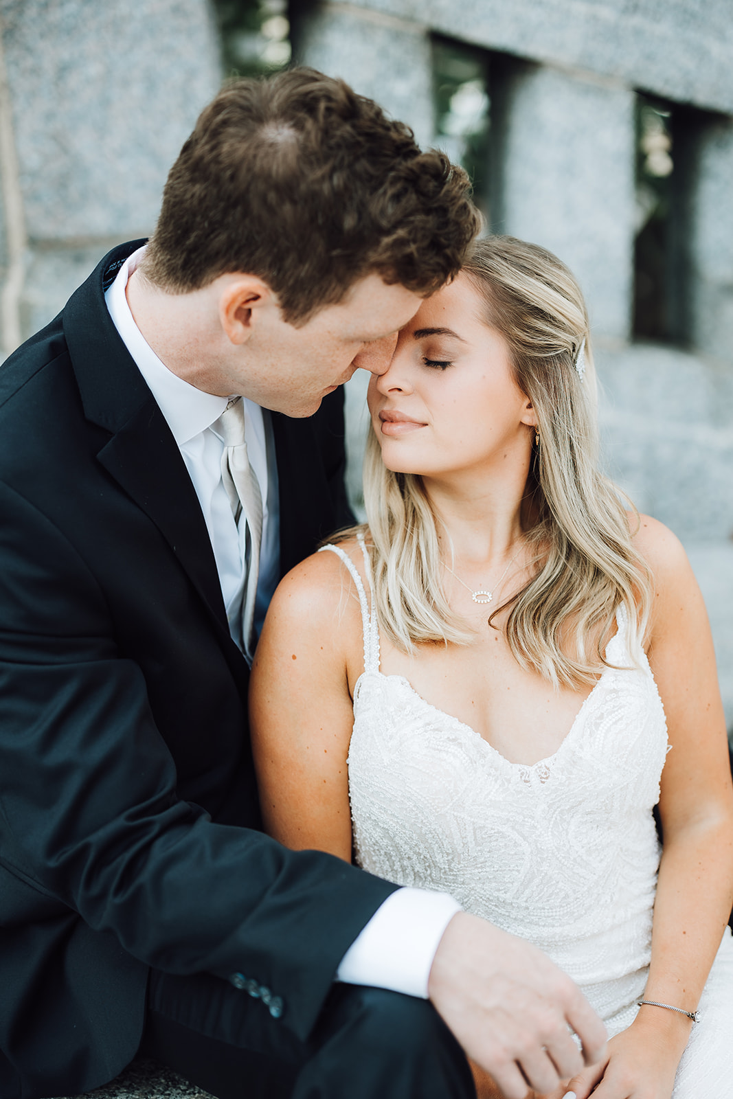 Newlyweds lean in for a kiss while sitting together on a bridge Union Station Wedding Nashville
