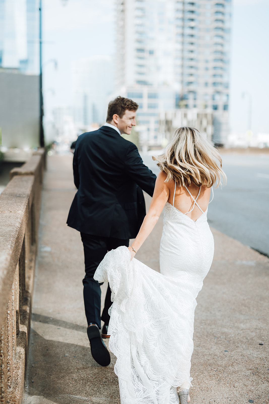 A groom in a black suit leads his bride by the hand down a dock Union Station Wedding Nashville