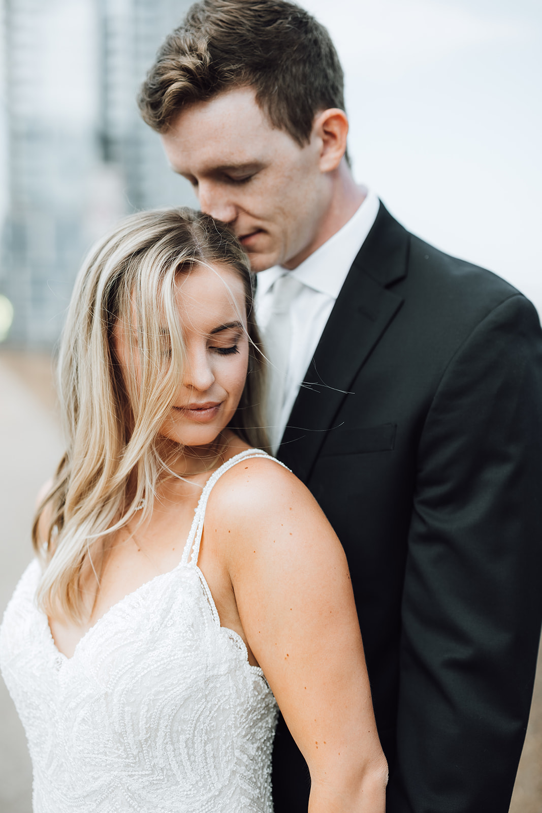 A bride leans into her husband's chest while standing against a building Union Station Wedding Nashville